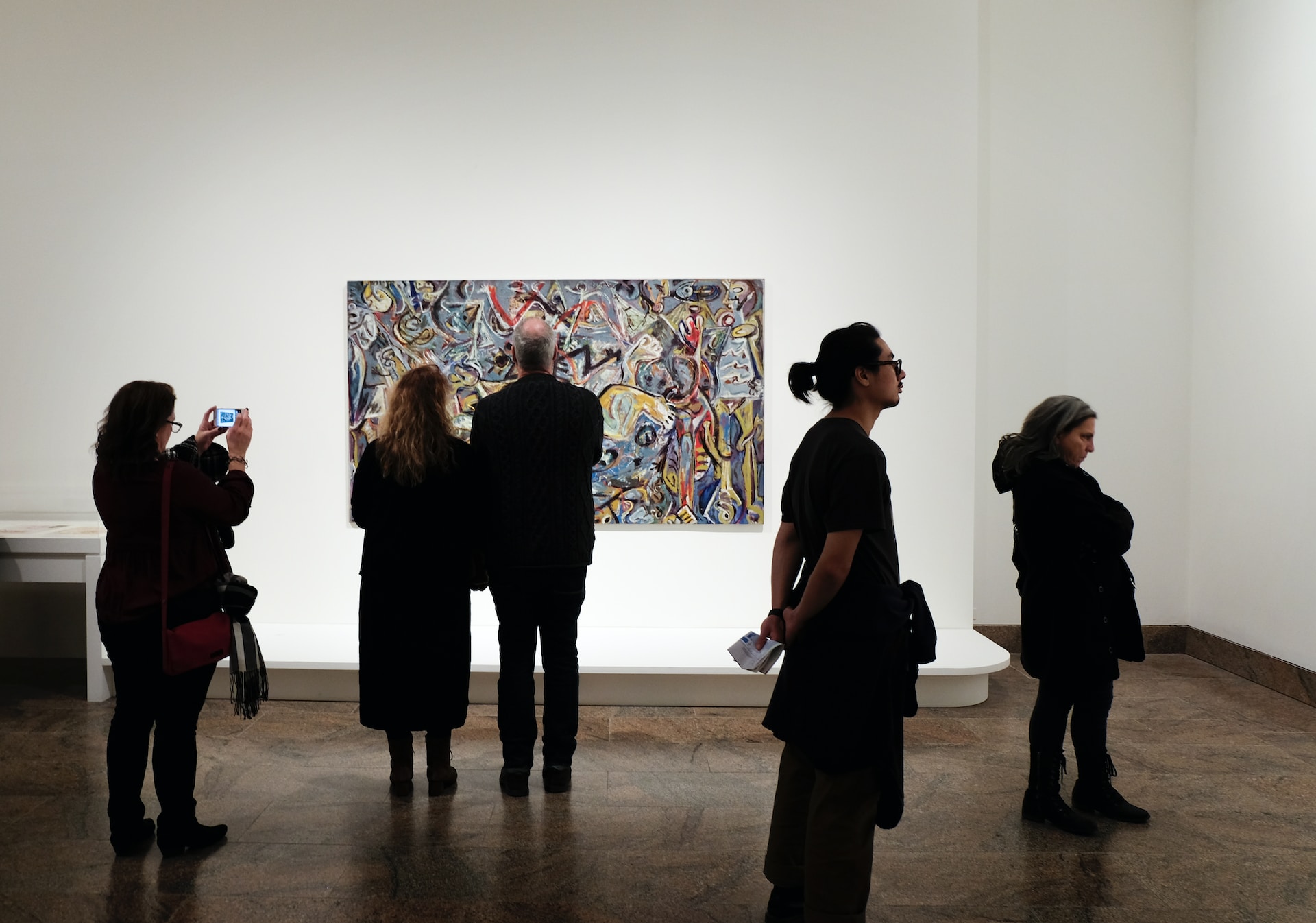 a group of people standing in front of a painting